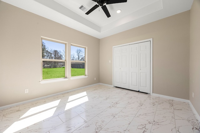 unfurnished bedroom featuring marble finish floor, visible vents, a raised ceiling, and baseboards