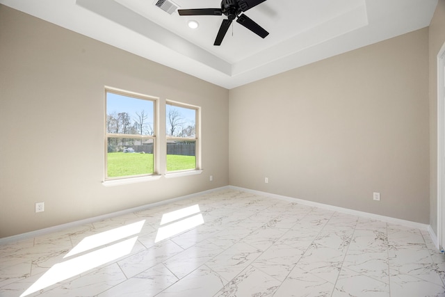 unfurnished room featuring marble finish floor, visible vents, a tray ceiling, and baseboards