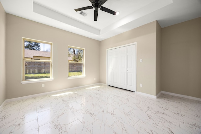 unfurnished bedroom with marble finish floor, baseboards, a raised ceiling, and a closet