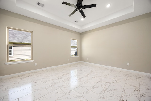 spare room featuring marble finish floor, baseboards, visible vents, and a raised ceiling