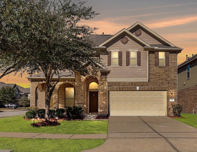 traditional-style house featuring driveway, an attached garage, a front yard, and brick siding