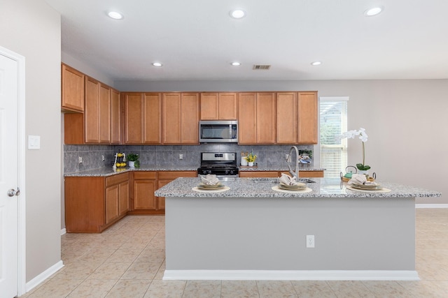 kitchen featuring visible vents, appliances with stainless steel finishes, a sink, light stone countertops, and backsplash