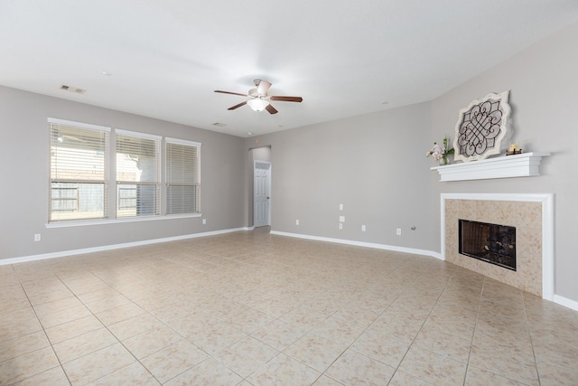 unfurnished living room with light tile patterned floors, baseboards, visible vents, a ceiling fan, and a tile fireplace