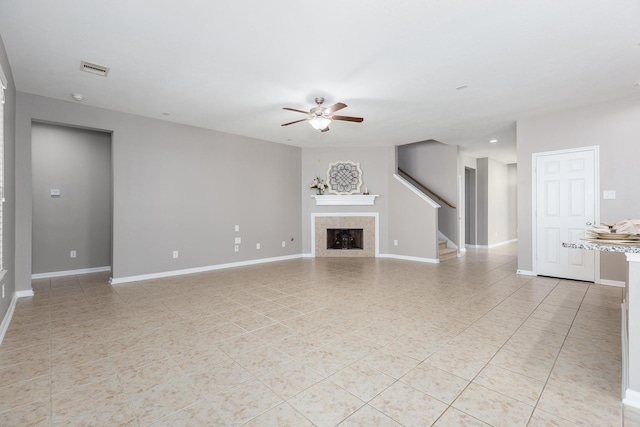 unfurnished living room featuring ceiling fan, a fireplace, stairs, and baseboards