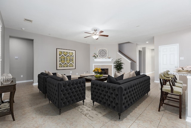 living room with a fireplace, light tile patterned floors, visible vents, a ceiling fan, and baseboards