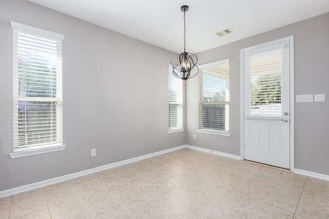 empty room with a chandelier, visible vents, and baseboards