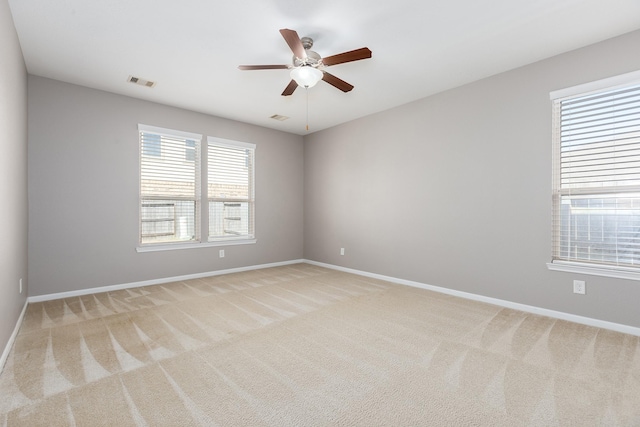 spare room with baseboards, ceiling fan, visible vents, and light colored carpet