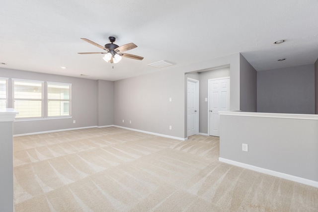 spare room featuring baseboards, ceiling fan, visible vents, and light colored carpet