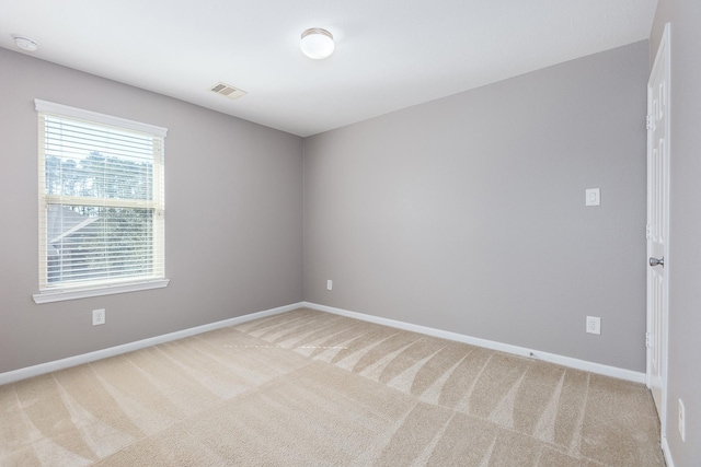 unfurnished room with baseboards, visible vents, and light colored carpet