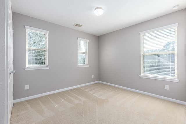 spare room with baseboards, visible vents, and light colored carpet