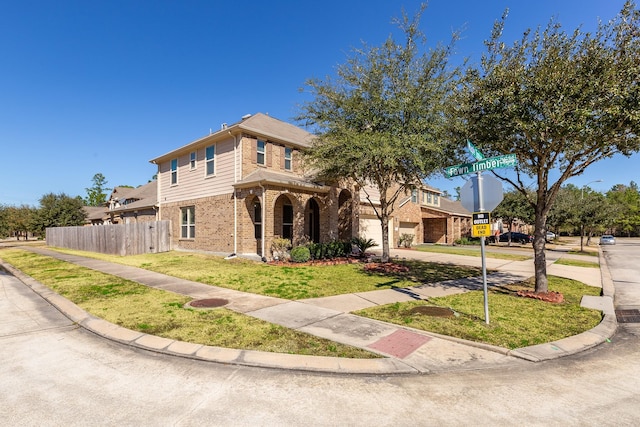 view of front of house featuring a front yard, fence, concrete driveway, and brick siding