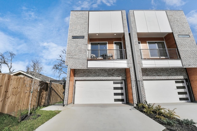 view of front of house featuring brick siding, fence, a balcony, a garage, and driveway