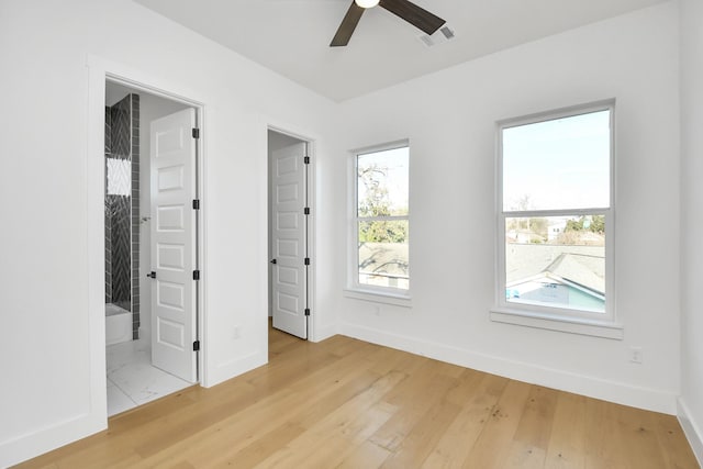 unfurnished bedroom featuring light wood finished floors, baseboards, a spacious closet, and visible vents