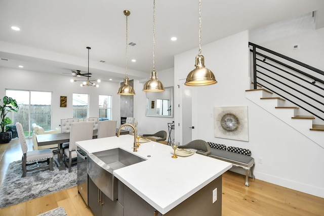 kitchen with a kitchen island with sink, recessed lighting, light wood-style floors, open floor plan, and light countertops