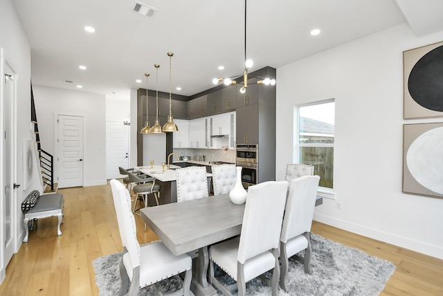 dining room featuring light wood-type flooring, baseboards, visible vents, and recessed lighting