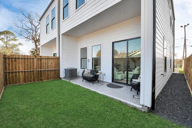 rear view of property with a yard, central AC unit, a patio area, and a fenced backyard