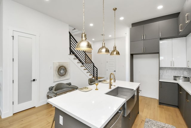 kitchen featuring recessed lighting, light countertops, gray cabinets, light wood finished floors, and tasteful backsplash