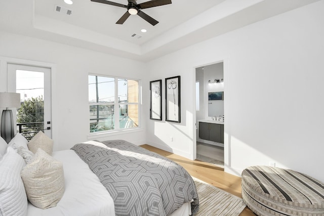 bedroom with light wood-type flooring, a raised ceiling, visible vents, and recessed lighting