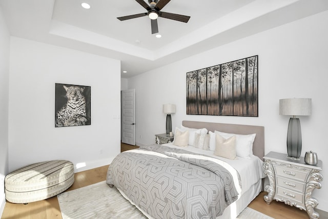 bedroom with ceiling fan, wood finished floors, a raised ceiling, and recessed lighting