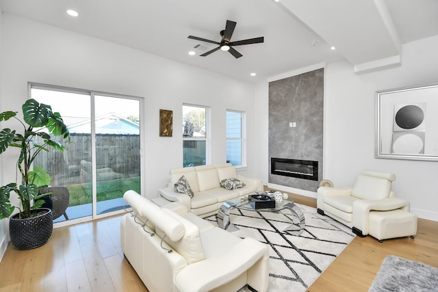 living room featuring light wood finished floors, baseboards, ceiling fan, a fireplace, and recessed lighting