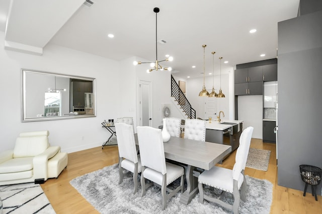 dining area featuring light wood-style floors, stairway, a notable chandelier, and recessed lighting