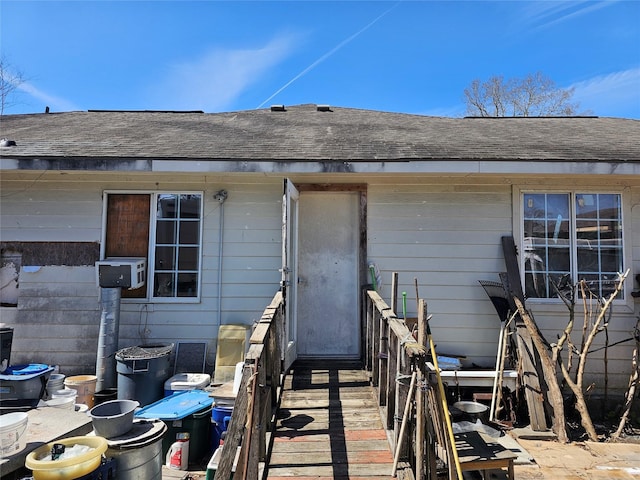 view of exterior entry featuring roof with shingles