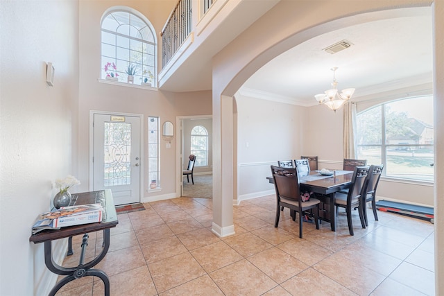 entryway with arched walkways, crown molding, light tile patterned floors, an inviting chandelier, and baseboards