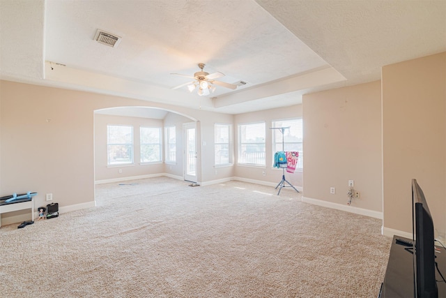 unfurnished room featuring light carpet, visible vents, a tray ceiling, and baseboards