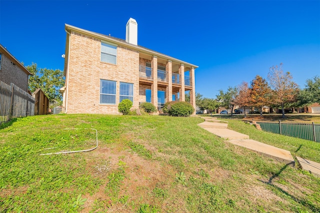 back of property featuring a yard, brick siding, a chimney, and fence