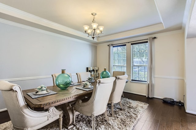 dining area with a notable chandelier, crown molding, a raised ceiling, dark wood finished floors, and baseboards