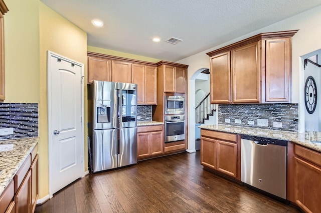 kitchen featuring arched walkways, appliances with stainless steel finishes, dark wood finished floors, and visible vents