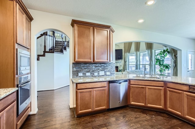 kitchen with decorative backsplash, arched walkways, a sink, and appliances with stainless steel finishes