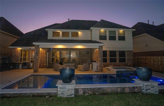 back of property at dusk with a patio, brick siding, and fence