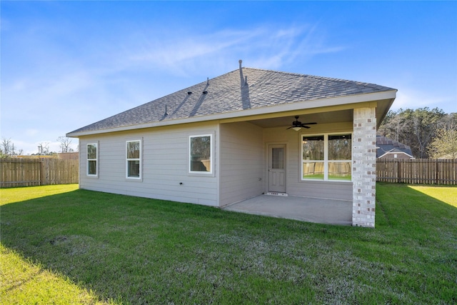 back of property with a ceiling fan, a patio area, a fenced backyard, and a lawn