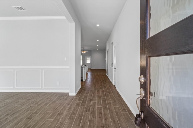 hallway featuring dark wood-style floors, visible vents, a decorative wall, and recessed lighting