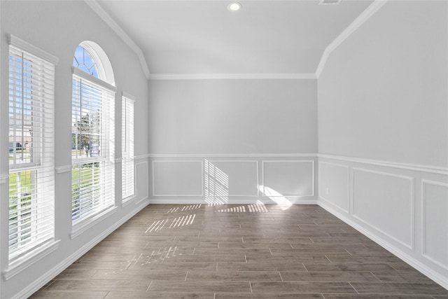 unfurnished room featuring wood finish floors, a wainscoted wall, crown molding, and a decorative wall