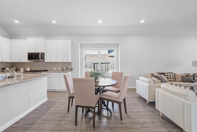 kitchen with white cabinets, backsplash, range, wood tiled floor, and stainless steel microwave