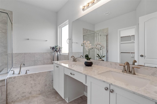 full bathroom featuring double vanity, a shower stall, a spacious closet, and a sink