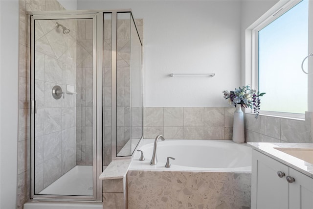 bathroom featuring a stall shower, a bath, and vanity