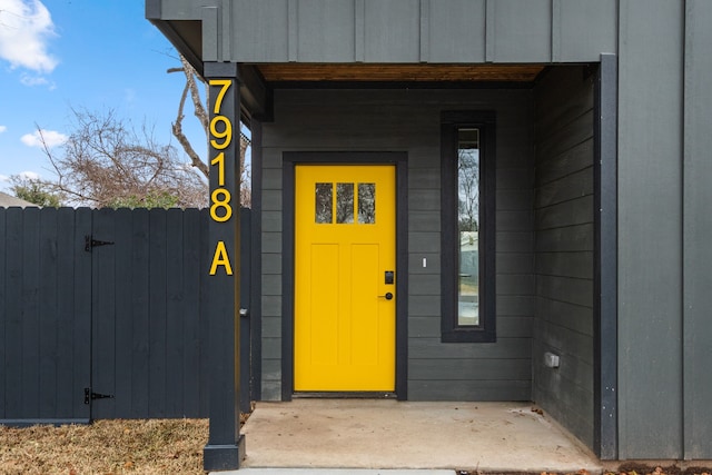 property entrance with board and batten siding and fence