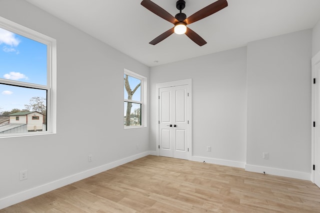 spare room with light wood finished floors, baseboards, and a ceiling fan