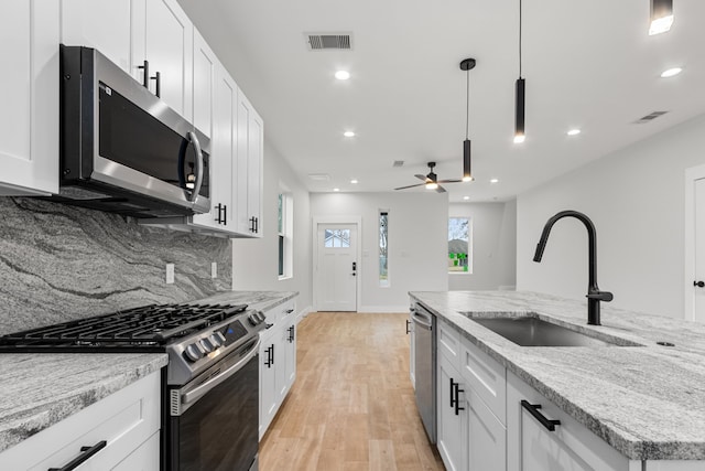 kitchen with visible vents, decorative backsplash, appliances with stainless steel finishes, light wood-type flooring, and a sink