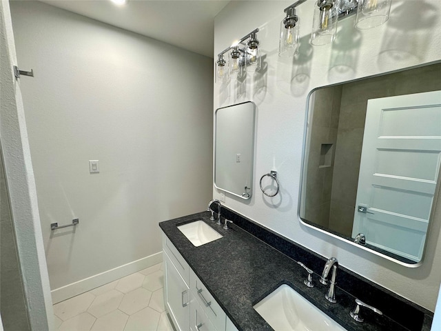 bathroom with double vanity, tile patterned flooring, a sink, and baseboards