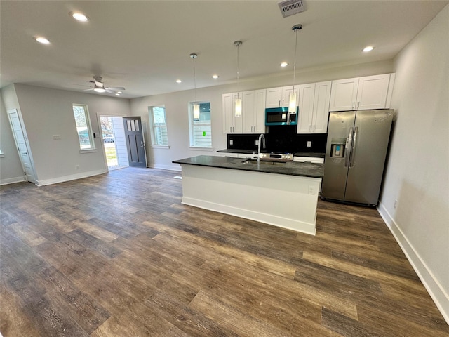 kitchen with dark countertops, visible vents, appliances with stainless steel finishes, white cabinets, and a sink