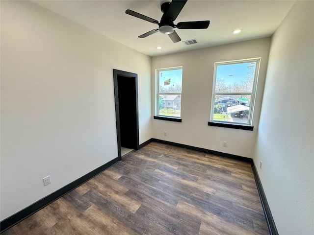 empty room with dark wood-type flooring, recessed lighting, visible vents, and baseboards