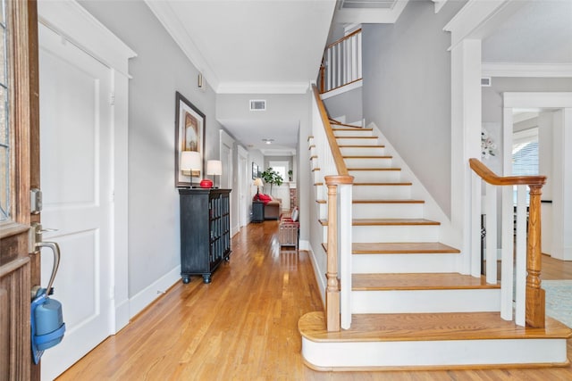 entryway featuring baseboards, visible vents, wood finished floors, and ornamental molding