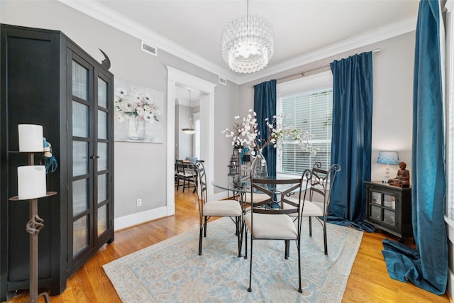 dining room with visible vents, baseboards, light wood-style flooring, ornamental molding, and a chandelier