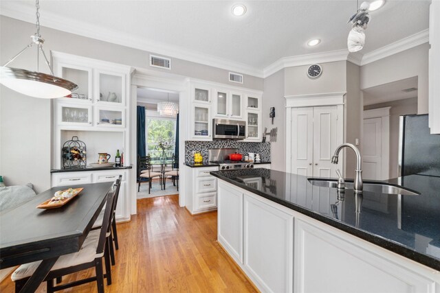 kitchen with white cabinetry, stainless steel microwave, a sink, and freestanding refrigerator