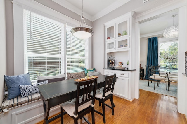 dining room with light wood-type flooring and crown molding