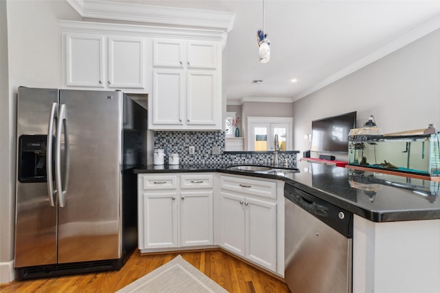 kitchen with stainless steel appliances, dark countertops, a sink, and ornamental molding